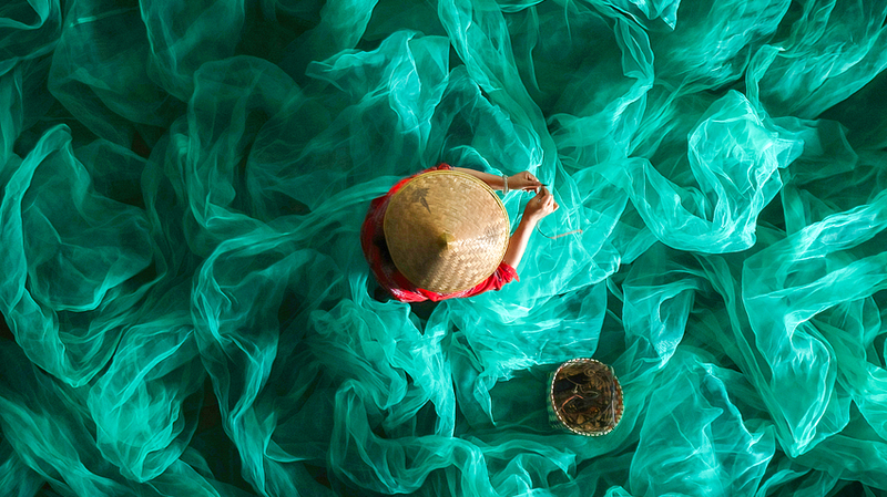 エメラルド色の漁網に浮かぶ漁師の女性──中国・福建省霞浦の海辺の日常